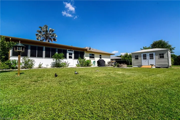 Back of property with an outdoor structure and a lawn