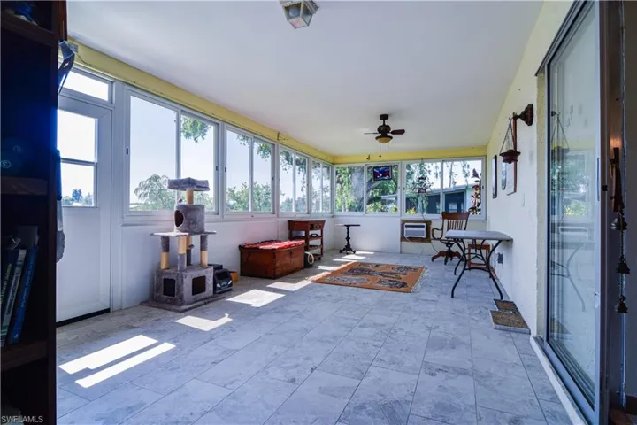 Sunroom featuring a wall mounted AC, plenty of natural light, and ceiling fan