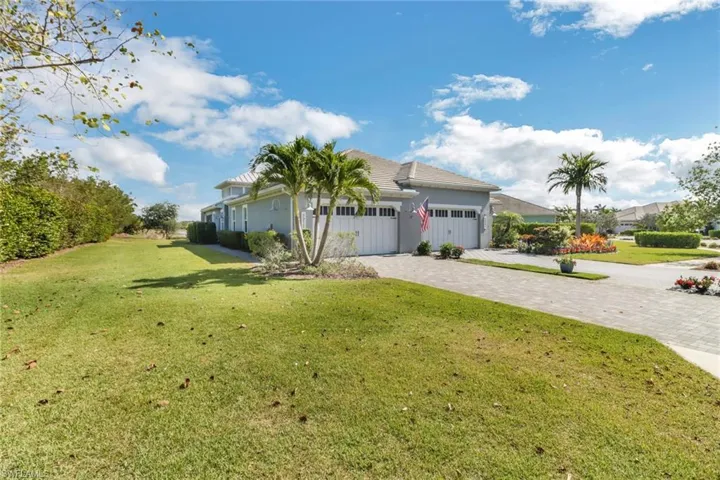 View of front of house featuring a front lawn, decorative driveway, stucco siding, and a garage