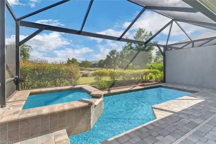 View of pool with glass enclosure, a patio, and a pool with connected hot tub