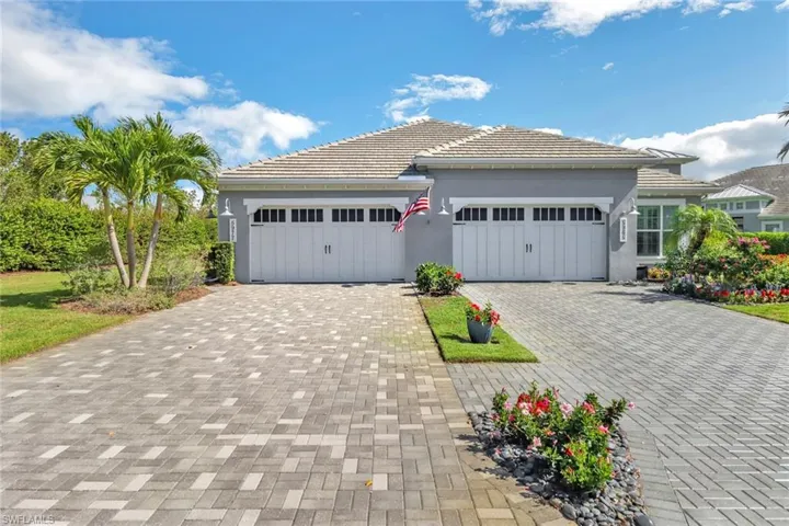 View of front of home featuring an attached garage, decorative driveway, a tile roof, and stucco siding