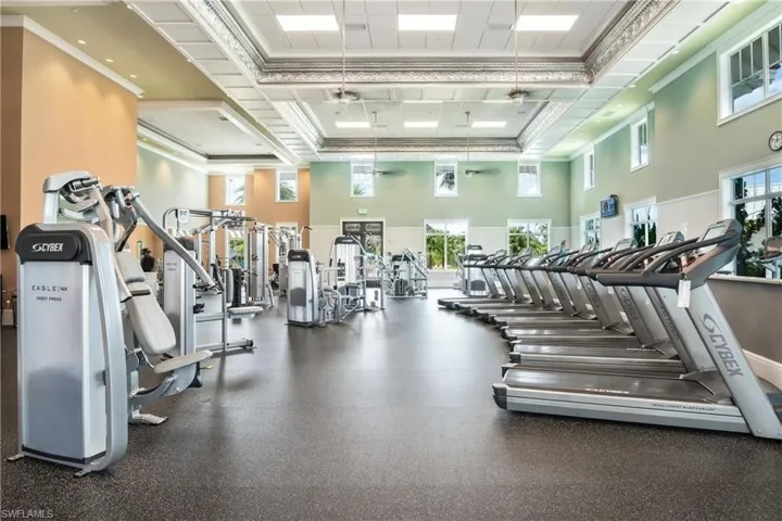 Gym featuring ceiling fan, ornamental molding, and a towering ceiling