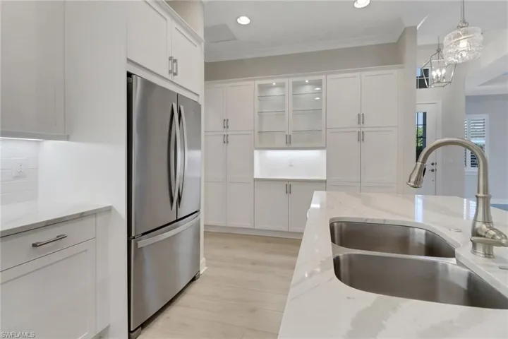 Kitchen with a sink, freestanding refrigerator, hanging light fixtures, and white cabinets