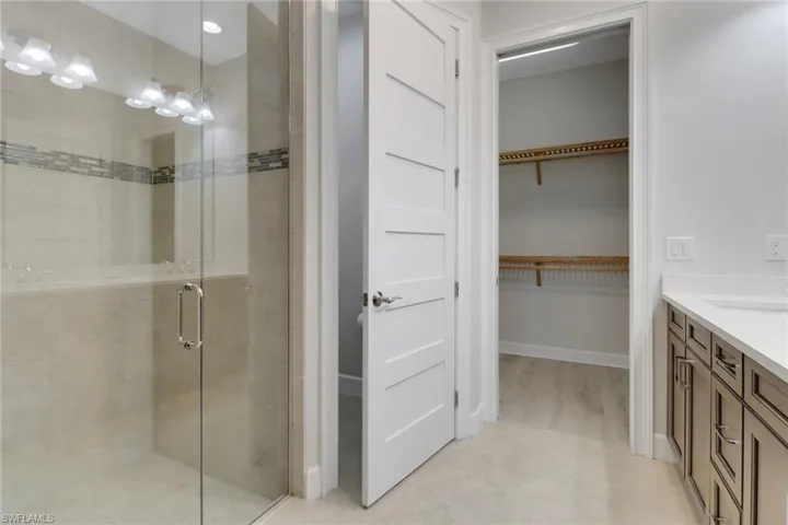 Bathroom with vanity, a spacious closet, a shower stall, and tile patterned flooring