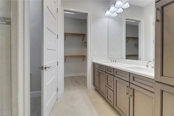 Bathroom with double vanity, a spacious closet, and a sink