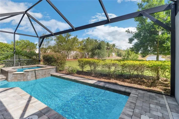 View of pool featuring a pool with connected hot tub, a patio, and a lanai