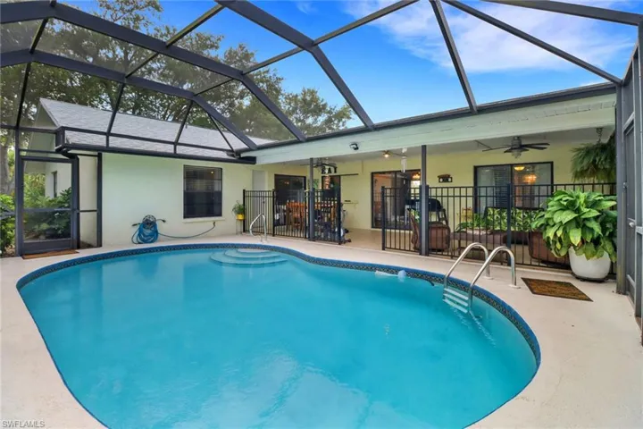 View of swimming pool with glass enclosure, ceiling fan, and a patio