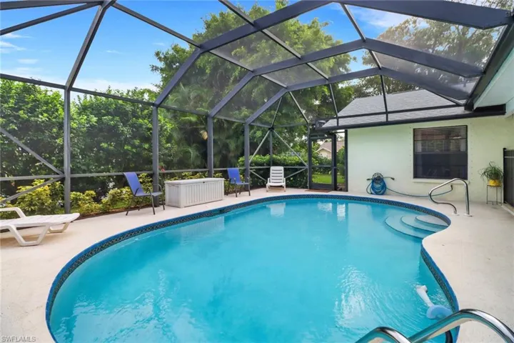 View of swimming pool with glass enclosure and a patio area