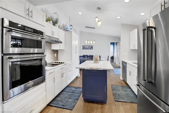 Kitchen featuring white cabinets, stainless steel appliances, a kitchen island, and light hardwood / wood-style floors