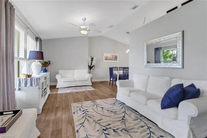 Living room featuring light hardwood / wood-style flooring, lofted ceiling, ceiling fan, and a wealth of natural light
