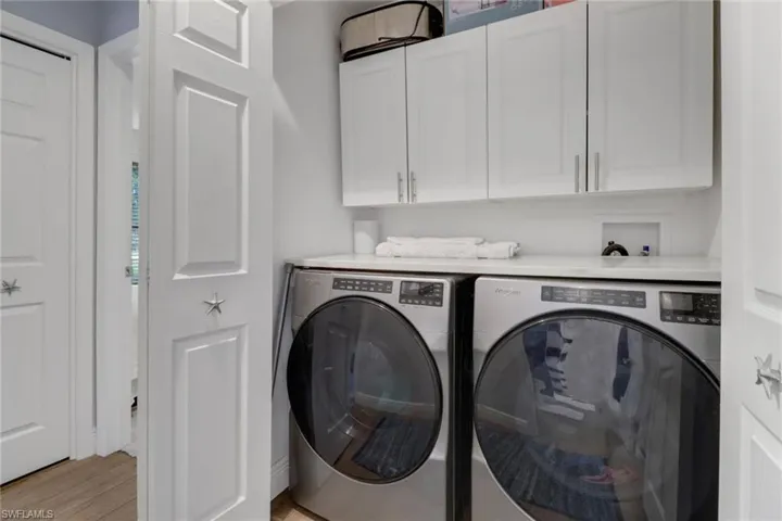 Laundry room featuring light wood-type flooring, cabinets, and washer and dryer