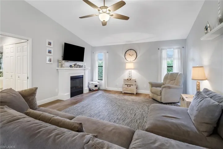 Living room with ceiling fan, plenty of natural light, wood-type flooring, and vaulted ceiling