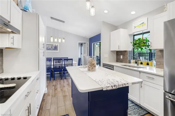 Kitchen featuring a kitchen island, pendant lighting, vaulted ceiling, tasteful backsplash, and sink