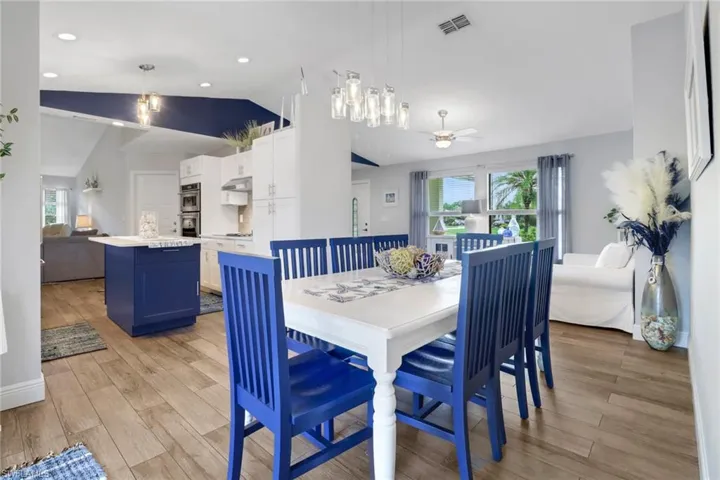 Dining room with ceiling fan, light wood-type flooring, and vaulted ceiling