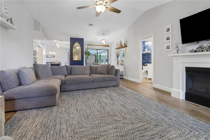 Living room with ceiling fan, hardwood / wood-style flooring, and vaulted ceiling