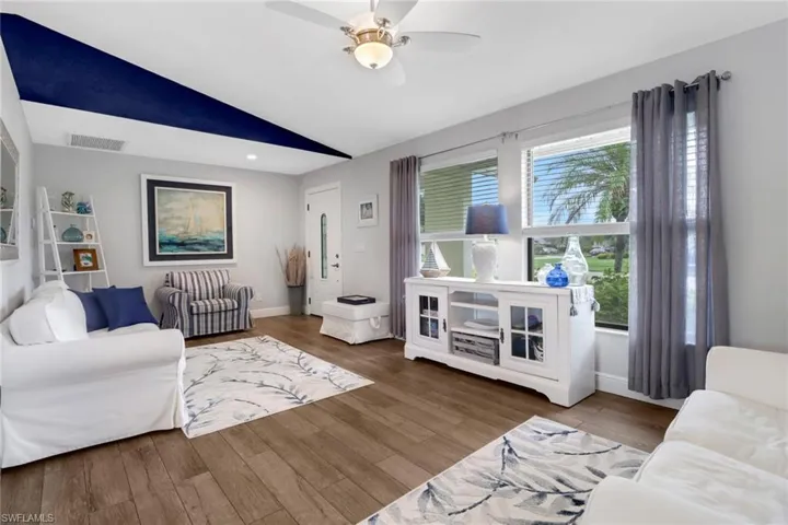 Living room with lofted ceiling, hardwood / wood-style floors, ceiling fan, and a wealth of natural light