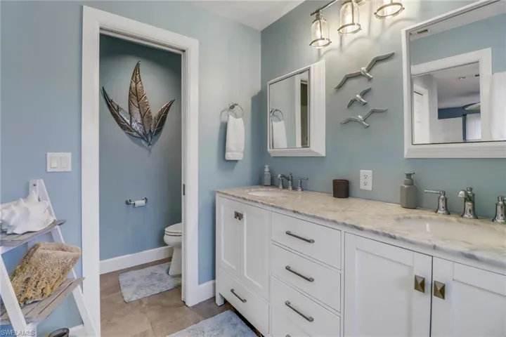Bathroom featuring toilet, dual bowl vanity, and tile patterned flooring