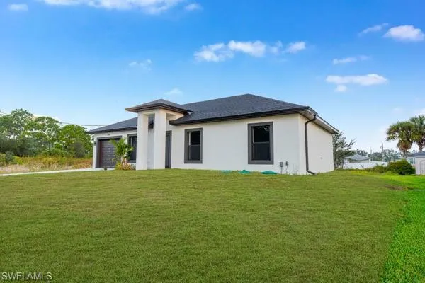 Prairie-style home with a front lawn, an attached garage, and stucco siding