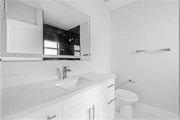 Full bath with vanity, light marble finish floors, and a tile shower