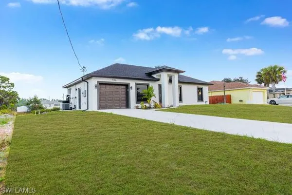 Prairie-style home with concrete driveway, a front lawn, a garage, and stucco siding