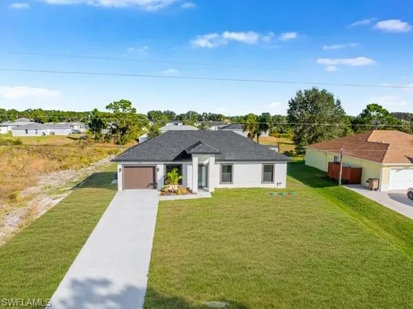 View of front of home with a front lawn, driveway, an attached garage, and stucco siding