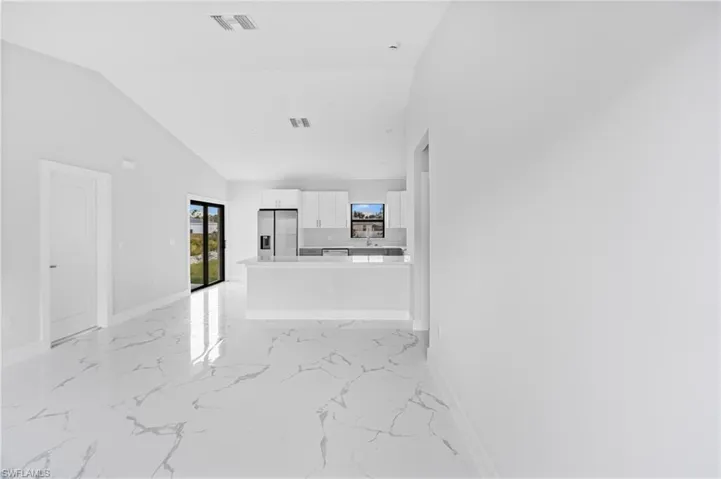 Unfurnished living room with light marble finish flooring and lofted ceiling
