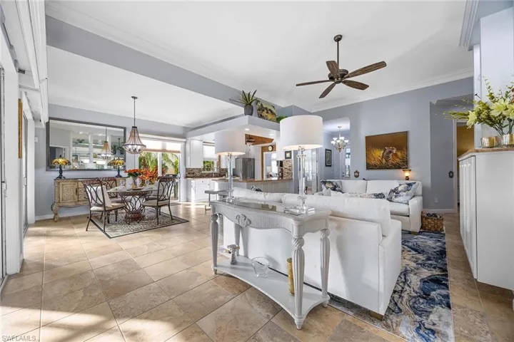 Living area featuring ornamental molding, a chandelier, and a ceiling fan