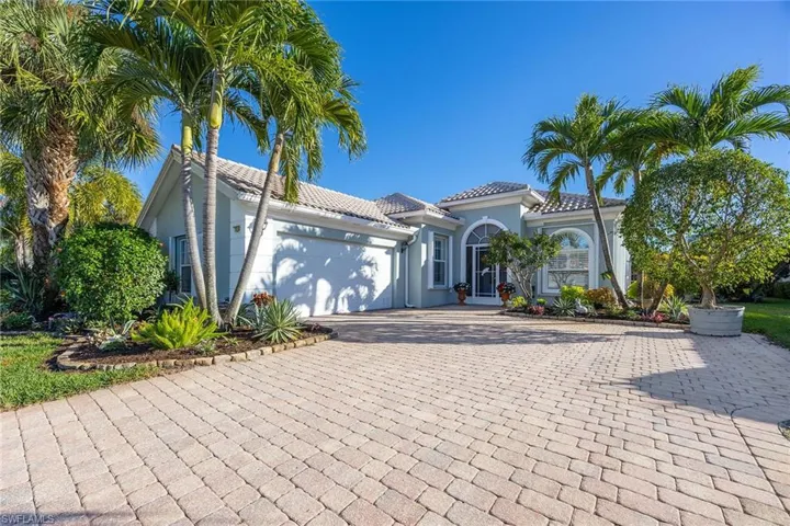 Mediterranean / spanish-style house with a garage, decorative driveway, stucco siding, and a tile roof