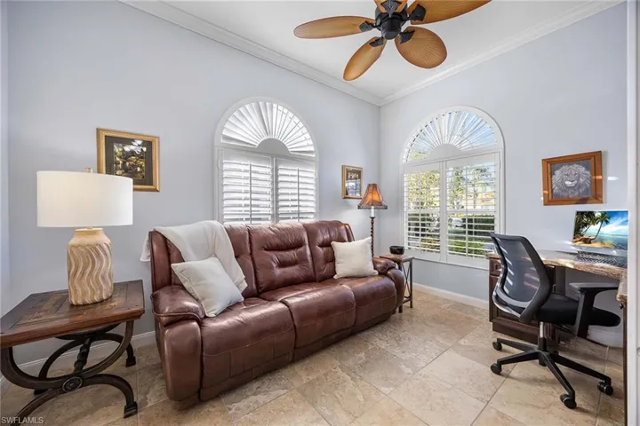 Office space with a ceiling fan, ornamental molding, healthy amount of natural light, and stone tile floors