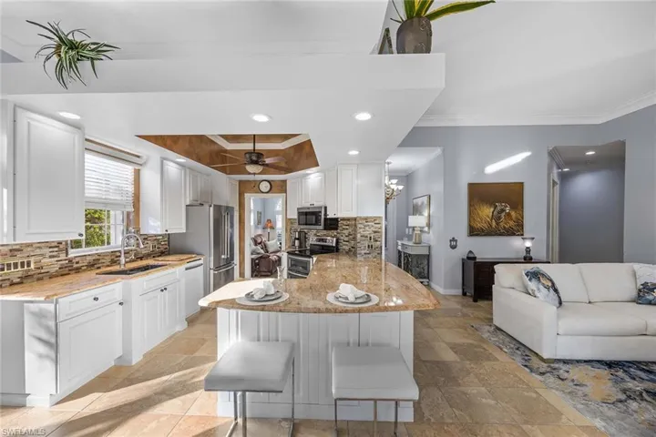 Kitchen with white cabinets, recessed lighting, open floor plan, decorative backsplash, and stainless steel appliances