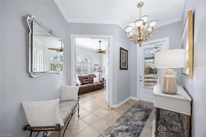 Entryway featuring ornamental molding, a chandelier, ceiling fan, and light tile patterned flooring