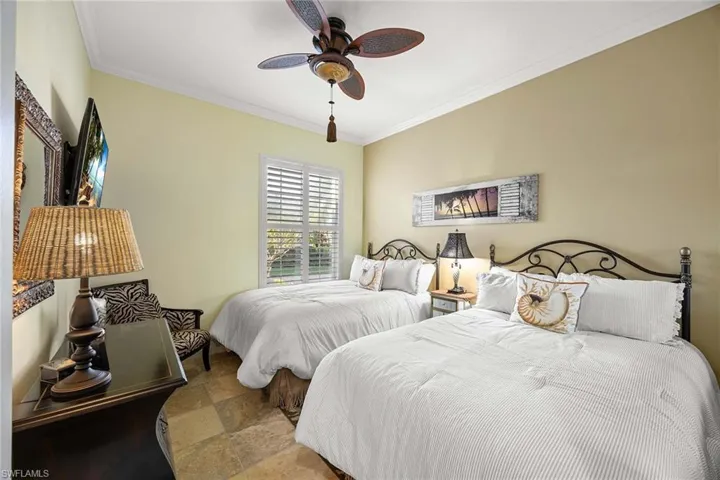 Bedroom with ornamental molding, a ceiling fan, and stone finish floors