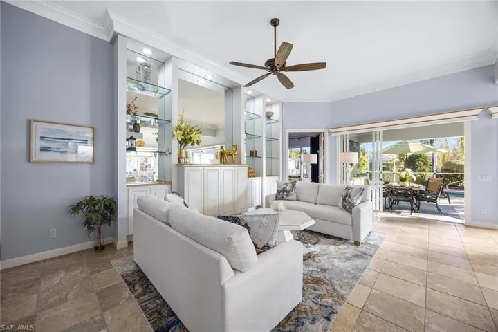Living room featuring ceiling fan, crown molding, and healthy amount of natural light