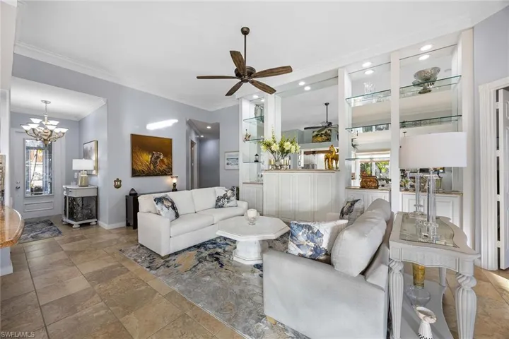 Living area featuring plenty of natural light, ceiling fan, crown molding, and stone tile flooring