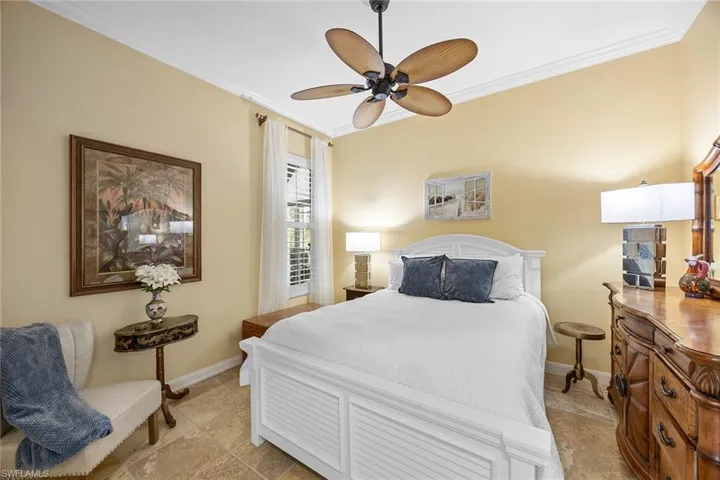 Bedroom featuring ornamental molding, stone tile flooring, and ceiling fan