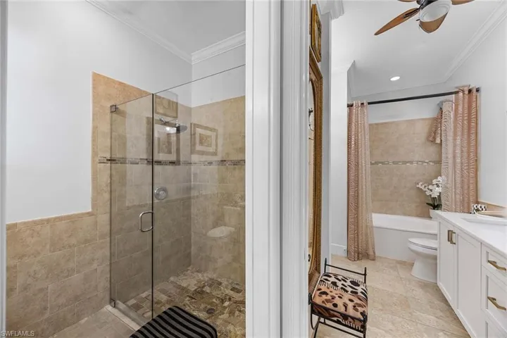 Full bathroom with vanity, ornamental molding, tiled shower / bath combo, and ceiling fan