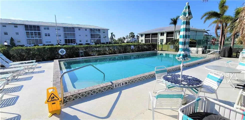 In-ground swimming pool featuring a tile perimeter border, concrete pool deck, and metal handrail