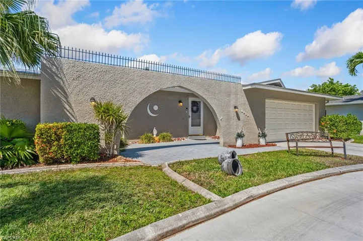 View of front of house with stucco siding, driveway, an attached garage, and a front yard