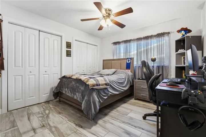 Bedroom featuring a desk, two closets, ceiling fan, and light wood-style floors