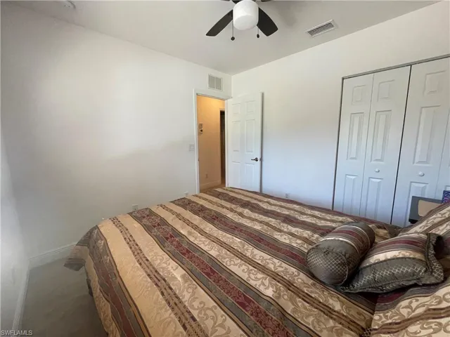 Carpeted bedroom with ceiling fan and a closet