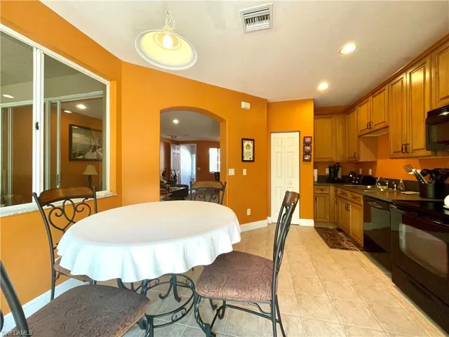 Kitchen with visible vents, black appliances, a sink, dark countertops, and arched walkways