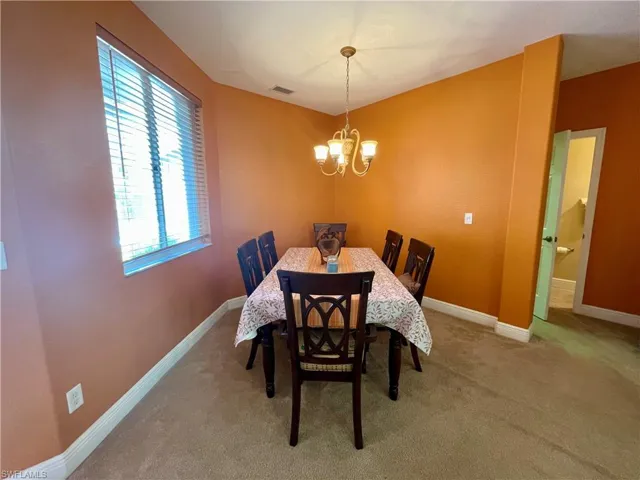 Dining area featuring a chandelier, baseboards, and carpet floors