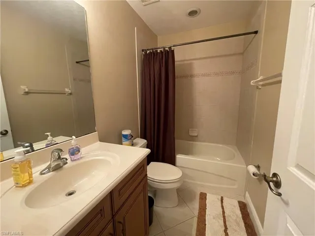 Full bathroom featuring tile patterned flooring, vanity, toilet, and shower / bath combo with shower curtain