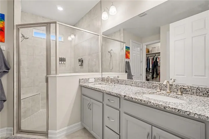 Full bath featuring a spacious closet, double vanity, and a shower