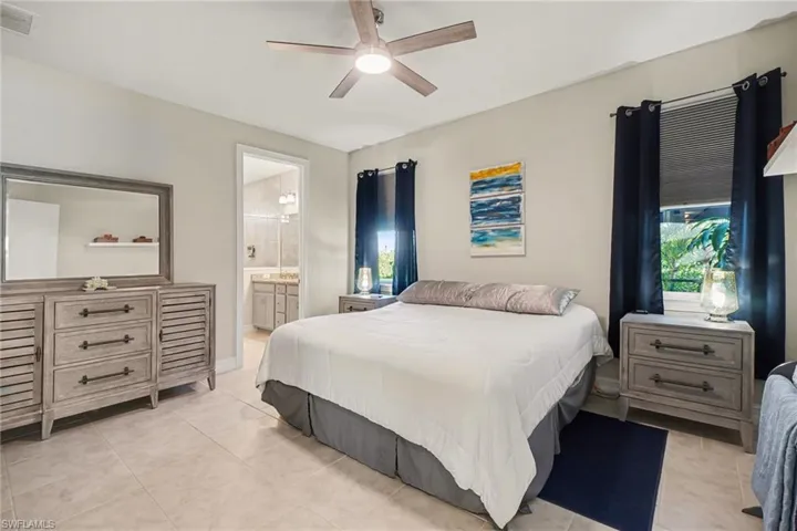 Bedroom with light tile patterned floors, a ceiling fan, and ensuite bathroom