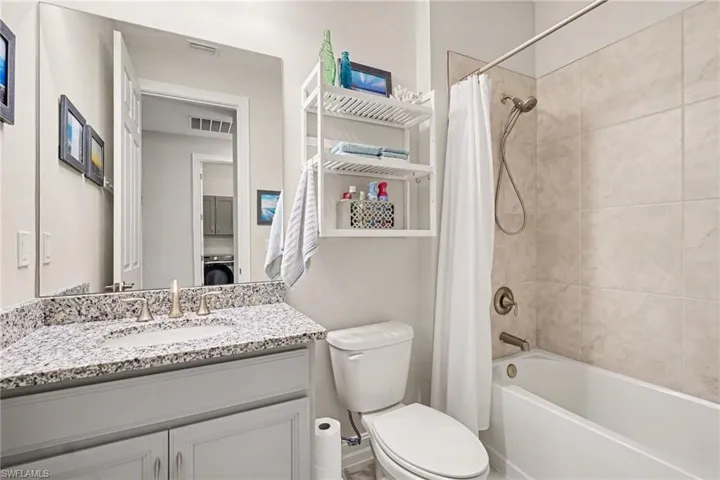 Full bathroom with vanity, shower / tub combo with curtain, and washer / clothes dryer