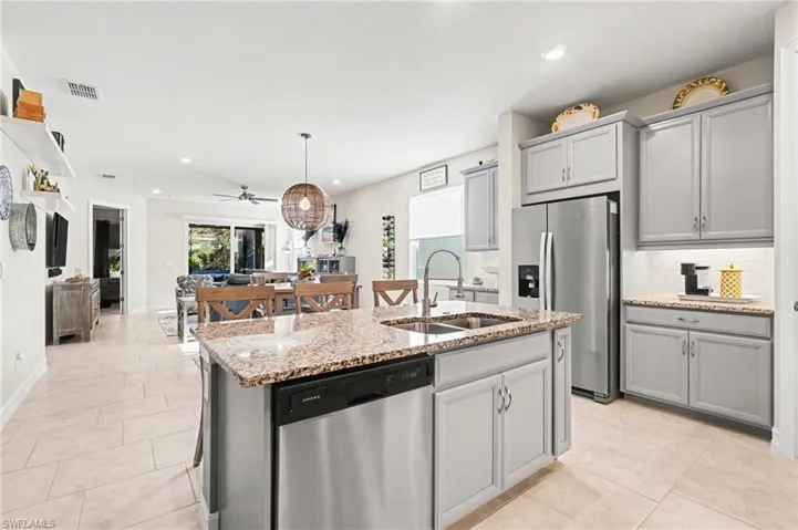 Kitchen featuring stainless steel appliances, light stone counters, and gray cabinetry