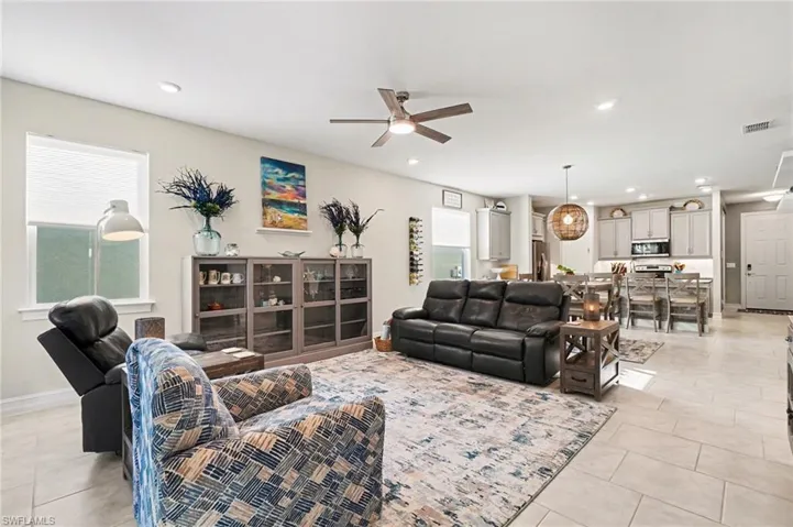 Living room with ceiling fan, light tile patterned floors, and recessed lighting