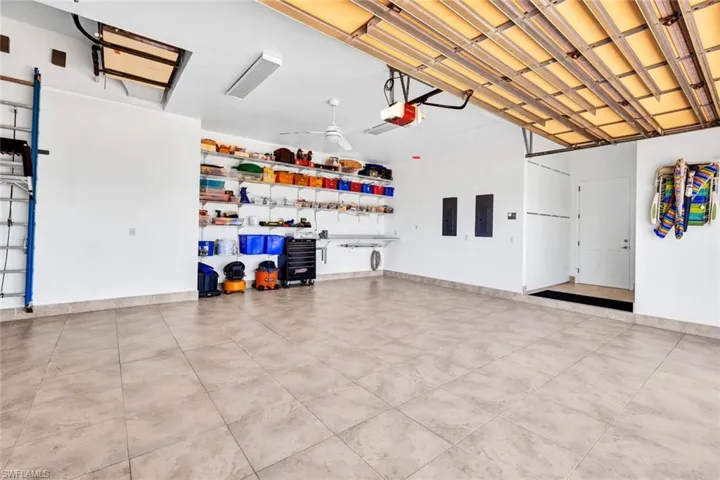 Garage featuring electric panel, a garage door opener, and baseboards