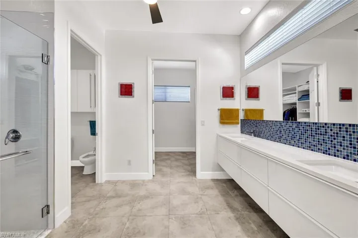Bathroom with backsplash, a stall shower, and a sink